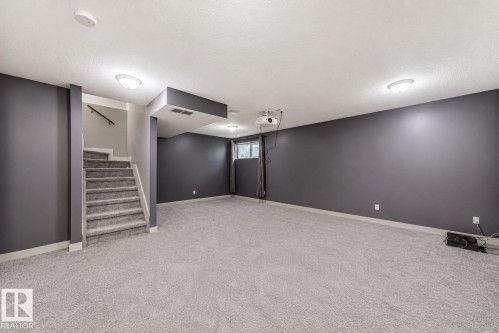 Spacious room featuring light gray carpeting, dark gray walls, and white trim - 1669 Hammond Crescent Nw, Edmonton, AB - Indoor
