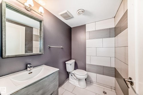 Bathroom featuring a vanity with an integrated sink, a rectangular framed mirror, and a three-light fixture - 1669 Hammond Crescent Nw, Edmonton, AB - Indoor Photo Showing Bathroom