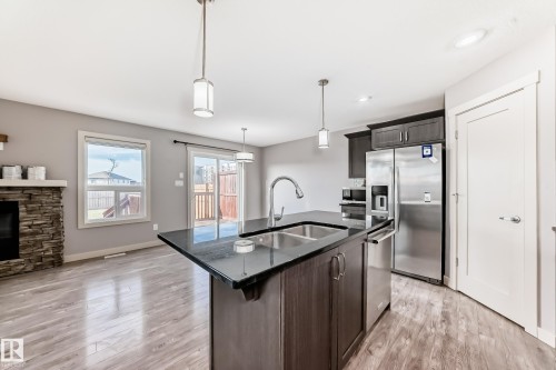 Kitchen island with a double basin stainless steel sink and dark countertop, complemented by dark wood-finish cabinetry - 1669 Hammond Crescent Nw, Edmonton, AB - Indoor Photo Showing Kitchen With Double Sink With Upgraded Kitchen