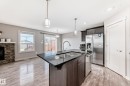 Kitchen island with a double basin stainless steel sink and dark countertop, complemented by dark wood-finish cabinetry - 1669 Hammond Crescent Nw, Edmonton, AB  - Indoor Photo Showing Kitchen With Double Sink With Upgraded Kitchen 