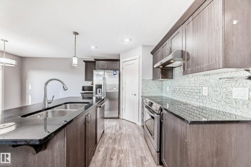 Kitchen featuring an expansive island with an undermount double sink, a gooseneck faucet, and pendant lighting - 1669 Hammond Crescent Nw, Edmonton, AB - Indoor Photo Showing Kitchen With Double Sink With Upgraded Kitchen