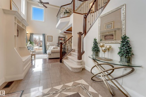 The property features a grand entryway with a high ceiling, a decorative tiled floor, and a staircase with a wrought iron railing - 6002 46 Avenue, Beaumont, AB - Indoor Photo Showing Other Room