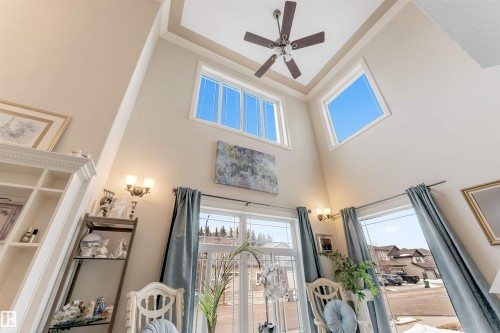 This living space features vaulted ceilings, large windows, and a ceiling fan - 6002 46 Avenue, Beaumont, AB - Indoor Photo Showing Other Room