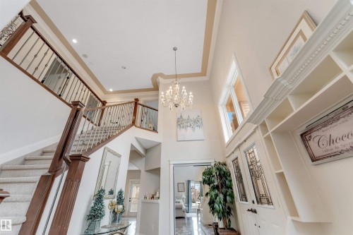 The property features a grand entryway with a double staircase, high ceilings, and an ornate chandelier - 6002 46 Avenue, Beaumont, AB - Indoor Photo Showing Other Room