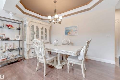 This room features hardwood floors and a tray ceiling with a chandelier - 6002 46 Avenue, Beaumont, AB - Indoor Photo Showing Dining Room