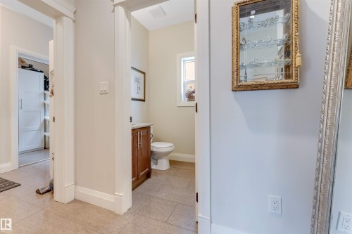 Well-appointed bathroom featuring a wooden vanity with a light-colored countertop, a toilet, and light-colored tiled flooring - 6002 46 Avenue, Beaumont, AB - Indoor Photo Showing Bathroom