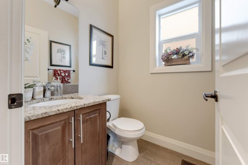 This bathroom features a vanity with a light-colored granite countertop, a white sink, and a brown wood cabinet with silver handles - 6002 46 Avenue, Beaumont, AB - Indoor Photo Showing Bathroom