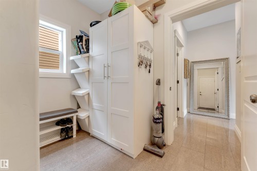 This mudroom area features a window with blinds, a built-in bench with shoe storage, and a tall white storage cabinet - 6002 46 Avenue, Beaumont, AB - Indoor
