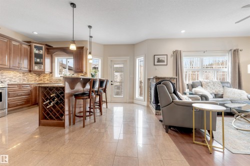 The property features a kitchen with warm-toned cabinetry, a tiled backsplash, and an integrated wine rack - 6002 46 Avenue, Beaumont, AB - Indoor
