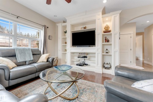 The living area features hardwood floors and a built-in entertainment unit with shelving and recessed lighting - 6002 46 Avenue, Beaumont, AB - Indoor Photo Showing Living Room
