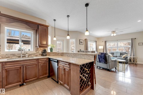 The kitchen features wood cabinetry, granite countertops, a tile backsplash, and a built-in wine rack - 6002 46 Avenue, Beaumont, AB - Indoor Photo Showing Kitchen