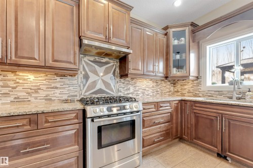 The kitchen features wood cabinetry, a stainless steel range with a matching range hood, and a tile backsplash - 6002 46 Avenue, Beaumont, AB - Indoor Photo Showing Kitchen With Upgraded Kitchen