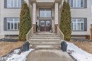 The property features a welcoming entrance with concrete steps and railings, flanked by tall evergreen shrubs - 6002 46 Avenue, Beaumont, AB  - Outdoor With Facade 