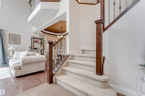 The property features an inviting entryway with a carpeted staircase and a dark wood banister - 6002 46 Avenue, Beaumont, AB - Indoor Photo Showing Other Room