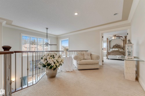 The property features a spacious landing with carpeted flooring, a decorative railing, and large windows providing natural light - 6002 46 Avenue, Beaumont, AB - Indoor Photo Showing Other Room