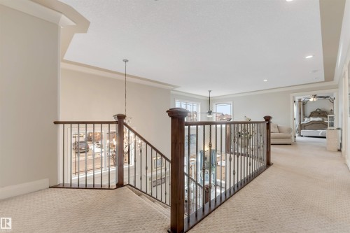 The property features a staircase with dark wood handrails and ornate metal balusters, and a carpeted landing - 6002 46 Avenue, Beaumont, AB - Indoor Photo Showing Other Room