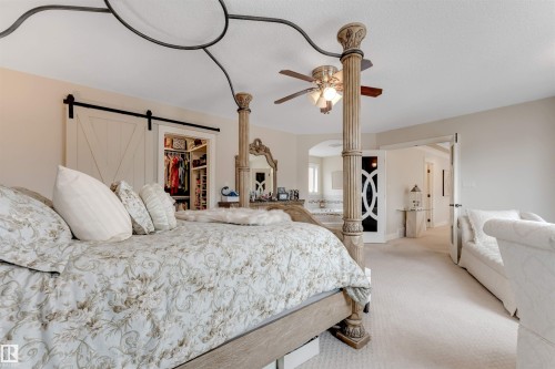 This inviting room features soft carpeting, a ceiling fan, and a large barn door revealing a well-organized closet space - 6002 46 Avenue, Beaumont, AB - Indoor Photo Showing Bedroom