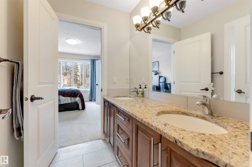 The property features a vanity with dual sinks, a granite countertop, and ample storage cabinetry - 6002 46 Avenue, Beaumont, AB - Indoor Photo Showing Bathroom
