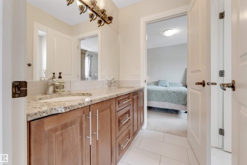 The bathroom features a double vanity with a granite countertop, undermount sinks, and ample storage cabinetry - 6002 46 Avenue, Beaumont, AB - Indoor Photo Showing Bathroom