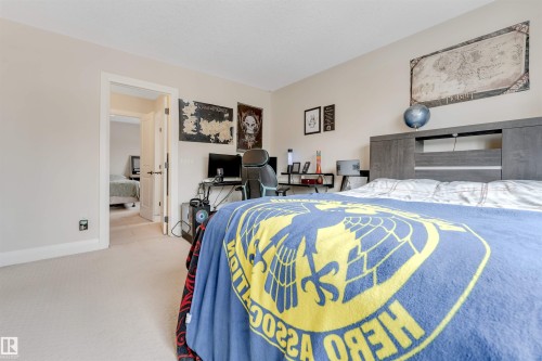 This room features neutral-toned walls, light-colored carpeting, and a doorway leading to an additional room - 6002 46 Avenue, Beaumont, AB - Indoor Photo Showing Bedroom