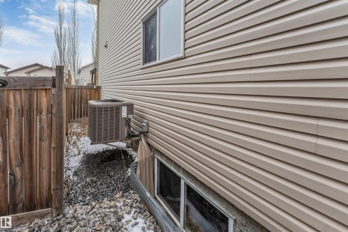 The property features beige horizontal siding, a fenced yard, and a window on the upper level, with an additional window below ground level - 6002 46 Avenue, Beaumont, AB - Outdoor With Exterior