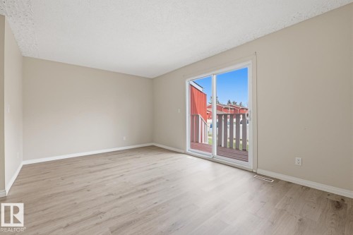 Spacious room featuring wood-finish flooring, neutral-toned walls, and white trim - 10640 Beaumaris Road, Edmonton, AB - Indoor Photo Showing Other Room