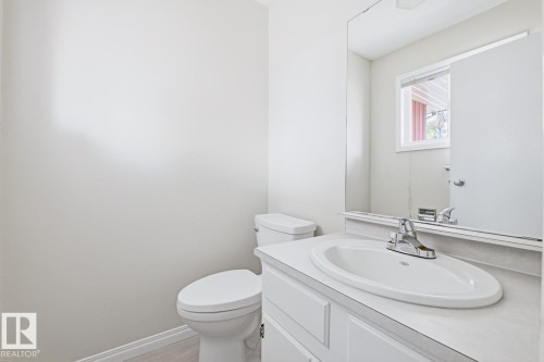 Bathroom featuring a white vanity with an integrated sink, chrome faucet, and a large wall-mounted mirror - 10640 Beaumaris Road, Edmonton, AB - Indoor Photo Showing Bathroom