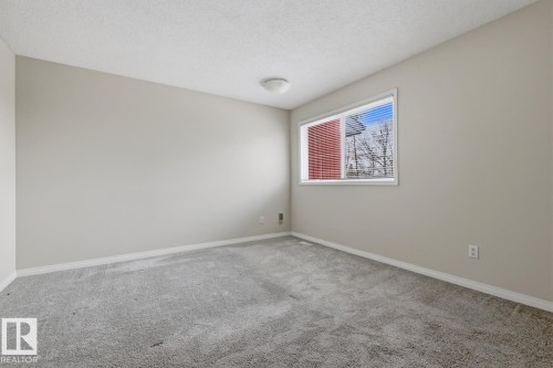 Carpeted room featuring neutral wall tones, white trim, and a window with horizontal blinds - 10640 Beaumaris Road, Edmonton, AB - Indoor Photo Showing Other Room