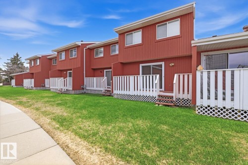Red-sided townhomes featuring white trim, private decks with lattice skirting, sliding glass doors, and upper-level windows - 10640 Beaumaris Road, Edmonton, AB - Outdoor With Exterior