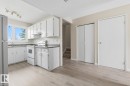 Kitchen featuring light wood-finish flooring, white cabinetry, dark countertops, a window over the sink, and white appliances including a refrigerator, range, and oven - 10640 Beaumaris Road, Edmonton, AB  - Indoor Photo Showing Kitchen 