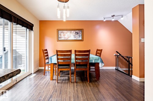 Dining space featuring wood-finish flooring, a contemporary ceiling light fixture, and a sliding glass door with integrated blinds - 40 12004 22 Avenue, Edmonton, AB - Indoor Photo Showing Dining Room