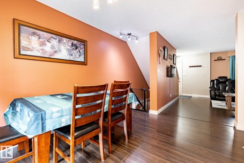 The dining area features hard flooring, a staircase with a railing, and a wall with a warm tone, leading to an additional living space - 40 12004 22 Avenue, Edmonton, AB - Indoor Photo Showing Dining Room