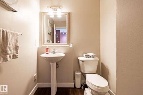 This bathroom features a pedestal sink with a chrome faucet, a toilet, and dark wood-look flooring - 40 12004 22 Avenue, Edmonton, AB - Indoor Photo Showing Bathroom