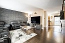Living area featuring a stone veneer accent wall and dark wood-finish flooring - 40 12004 22 Avenue, Edmonton, AB  - Indoor Photo Showing Living Room 
