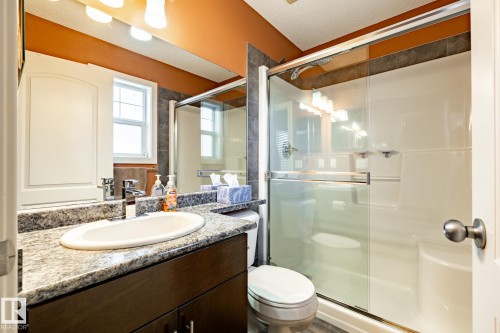 Bathroom featuring a vanity with a granite countertop, a shower with a sliding glass door, and a toilet - 40 12004 22 Avenue, Edmonton, AB - Indoor Photo Showing Bathroom