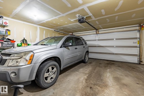 The garage features a concrete floor, an overhead garage door, and a garage door opener - 40 12004 22 Avenue, Edmonton, AB - Indoor Photo Showing Garage