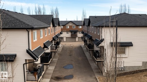 The property features a multi-story exterior with dark shingled roofs and contrasting light and dark siding - 40 12004 22 Avenue, Edmonton, AB - Outdoor With Exterior
