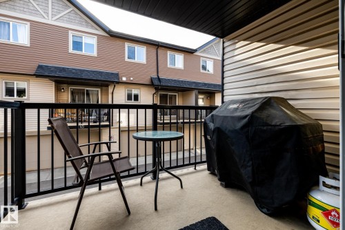The property features a private covered balcony with a concrete floor and black metal railings - 40 12004 22 Avenue, Edmonton, AB - Outdoor With Exterior