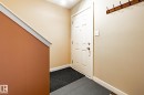Entryway featuring a paneled door with polished hardware, a wall-mounted wooden coat rack with metal hooks, and neutral-toned walls - 40 12004 22 Avenue, Edmonton, AB  - Indoor Photo Showing Other Room 