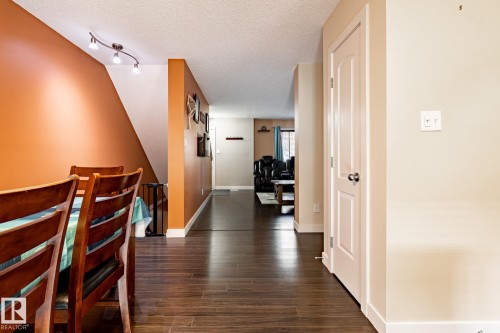 The main living area features dark wood flooring, a warm orange accent wall, and track lighting - 40 12004 22 Avenue, Edmonton, AB - Indoor Photo Showing Other Room