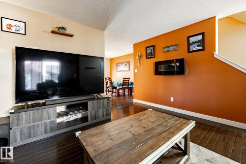 The property features hard surface flooring, a wall-mounted electric fireplace, and a dining area visible from the living space - 40 12004 22 Avenue, Edmonton, AB - Indoor Photo Showing Living Room