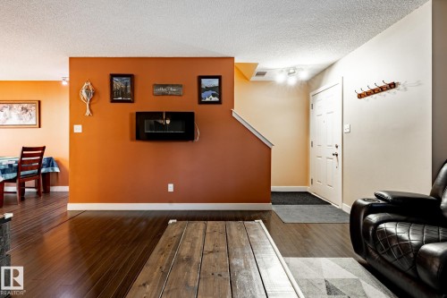 Living area featuring rich hardwood floors, an electric fireplace, and a white entry door - 40 12004 22 Avenue, Edmonton, AB - Indoor