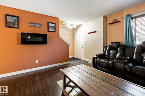 The living space features rich, dark wood flooring and a wall-mounted fireplace - 40 12004 22 Avenue, Edmonton, AB - Indoor