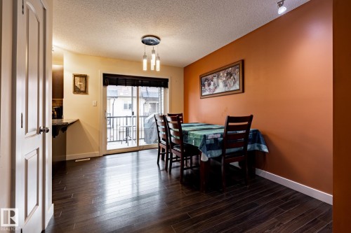 Dining area featuring dark wood flooring, a modern chandelier, and sliding glass doors that open to a balcony - 40 12004 22 Avenue, Edmonton, AB - Indoor Photo Showing Dining Room
