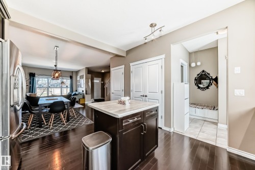 Kitchen island with a light-toned countertop, dark wood-finish cabinetry, and stainless steel hardware - 5020 Orchards Gate, Edmonton, AB - Indoor Photo Showing Other Room