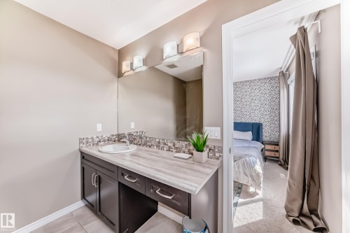 Bathroom vanity with a white oval sink, chrome faucet, and mosaic tile backsplash - 5020 Orchards Gate, Edmonton, AB - Indoor Photo Showing Bathroom