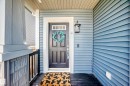 Front entry featuring blue horizontal siding, a black paneled door with transom window, and a dark wood-finish porch floor - 5020 Orchards Gate, Edmonton, AB  - Outdoor With Exterior 
