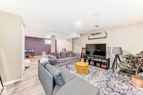 Open concept living area featuring light wood-finish flooring, recessed lighting, and a large area rug - 5020 Orchards Gate, Edmonton, AB - Indoor Photo Showing Living Room