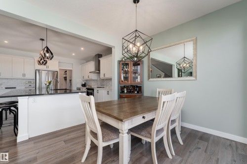 Formal dining area featuring wood-finish flooring, a contemporary chandelier, and a built-in display cabinet - 1450 Darby Green, Edmonton, AB - Indoor Photo Showing Dining Room