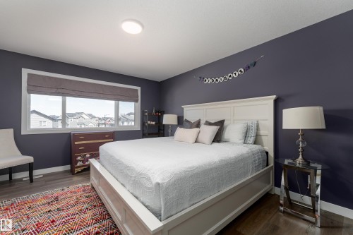 Wood-finish flooring throughout, featuring a large window with privacy blinds, recessed ceiling light, and deep-toned walls - 1450 Darby Green, Edmonton, AB - Indoor Photo Showing Bedroom